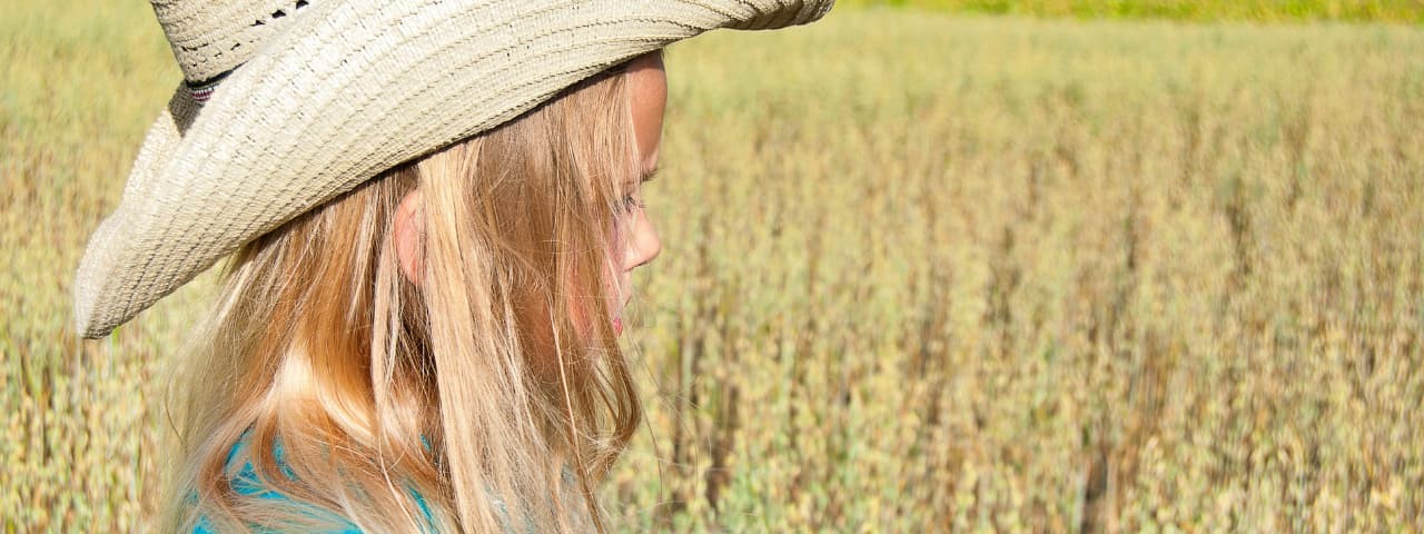  Close-up of a blonde girl in a straw hat in the countryside